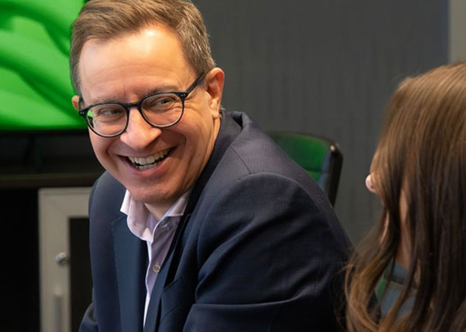 Two colleagues smiling in conversation during a meeting.